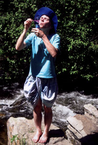 Blowing bubbles by the stream.